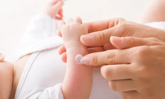 Application de cicalfate nourrisson sur le bras d'un bébé par une main douce.