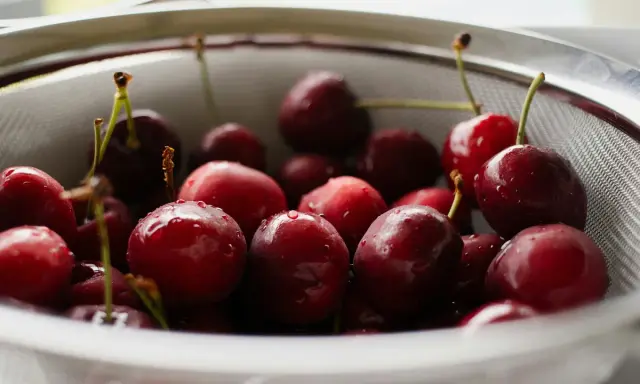 Frisch gewaschene Kirschen in einem Sieb, bereit für das Einkochen ohne Zucker.