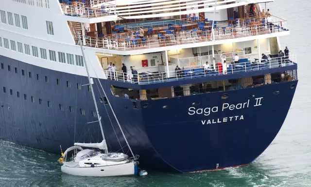 La nave da crociera "Saga Pearl II" è imponente accanto a una piccola barca a vela, mostrando la differenza tra nave e traghetto.