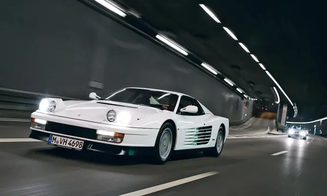 Weißer Ferrari Testarossa fährt durch einen beleuchteten Tunnel.