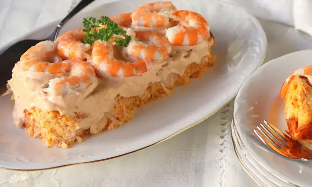 Pastel de pescado para Navidad, cubierto con una cremosa salsa rosada y adornado con gambas. Un entrante festivo y delicioso.