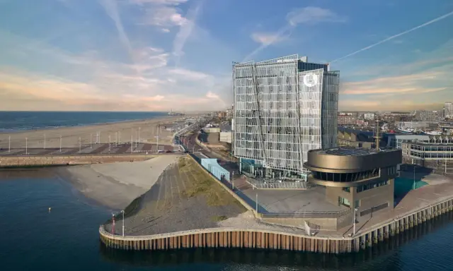 Modernes Hotel am Meer mit Glasfassade, Strand und Hafen.