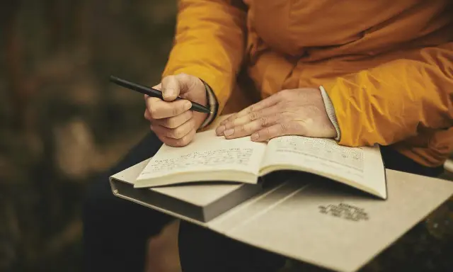 Mani che scrivono su un quaderno aperto, ispirate dalle riviste letterarie italiane.