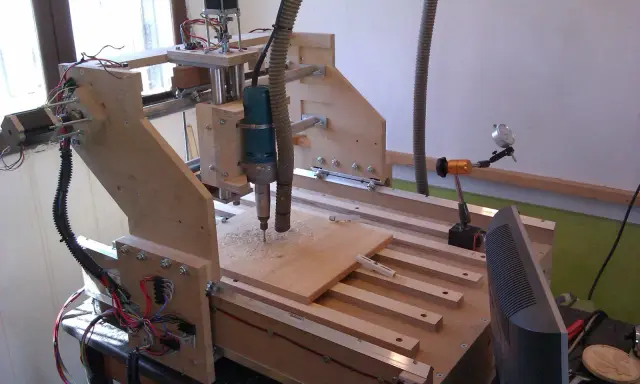 Macchina **cnc fai da te** in legno, con fresa in azione su un pannello.