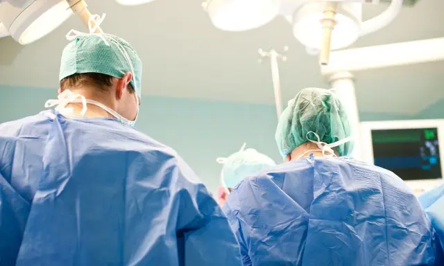 Chirurdzy w zielonych czepkach i niebieskich fartuchach przygotowują się do klasycznej operacji prostaty.