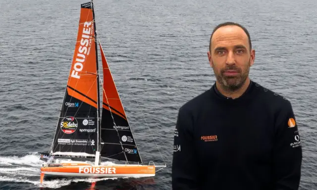 Sébastien Marsset, skipper du voilier Foussier, prêt pour la course. Le bateau orange et noir fend les vagues.