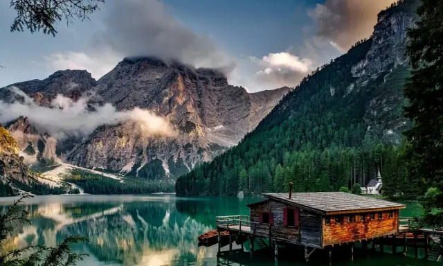 Lago alpino con baita in legno e montagne nebbiose. Curiosità sul Trentino Alto Adige: un luogo da fiaba.