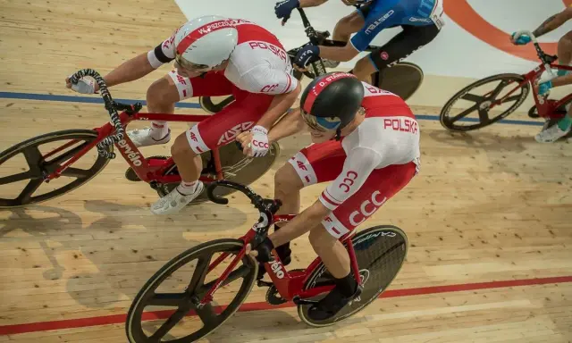 Wyścig kolarski madison. Dwóch kolarzy w biało-czerwonych strojach jedzie na torze.