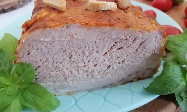 Soczysty schab pieczony w mleku, z czosnkiem i bazylią, prezentuje się apetycznie na talerzu.