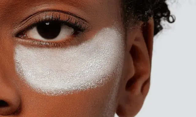 Primo strato di cipria prima del fondotinta, evidenzia la texture della pelle e la preparazione per un makeup impeccabile.