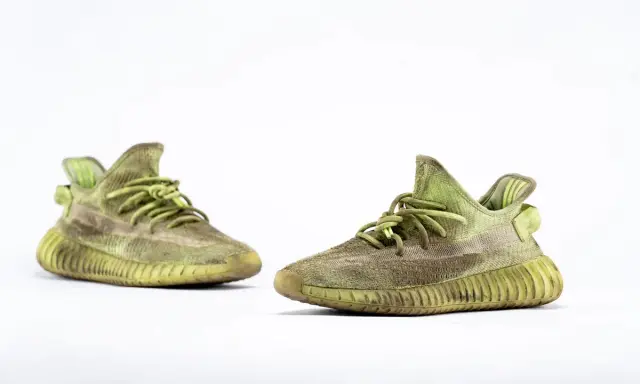 Para zielonych adidas Yeezy 350 z charakterystyczną, prążkowaną podeszwą, gotowe na miejskie przygody.