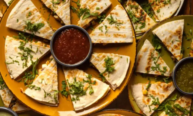 Pyszna quesadilla z mięsem mielonym, pokrojona w trójkąty, podana z salsą i zielonym sosem.
