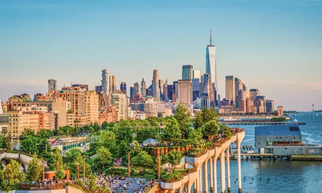 En grönskande park på pelare med New Yorks skyline i bakgrunden. Perfekt för tips på nya upplevelser i New York.