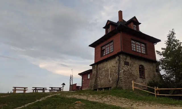 Drewniana wieża widokowa na Luboniu Wielkim, z kamiennym fundamentem, otoczona zielenią i ławkami.