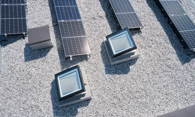 Vue aérienne d'une maison toit plat avec panneaux solaires et deux fenêtres de toit.