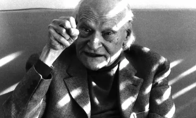 Ritratto di un anziano con pugno alzato, in memoria di Ungaretti. Le rughe sul volto e la luce che lo illumina creano un'atmosfera intensa.