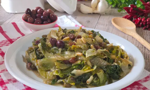 Scarola in padella con olive, pinoli e uvetta, un contorno saporito e colorato.