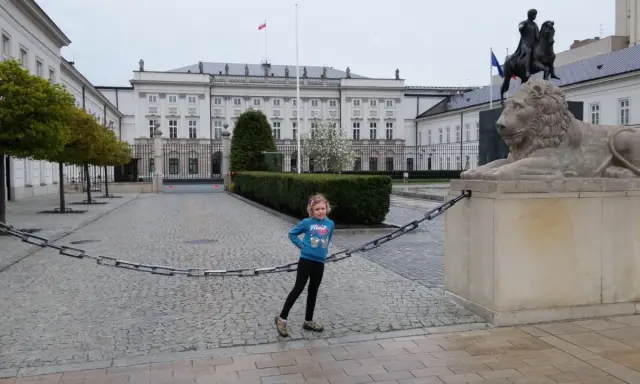 Dziewczynka na trasie traktu królewskiego w Warszawie, obok lwa i pomnika konnego.