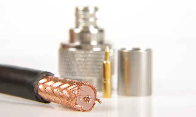 Przewód ekranowany z miedzianym oplotem, obok złoty pin i metalowe złącza.
