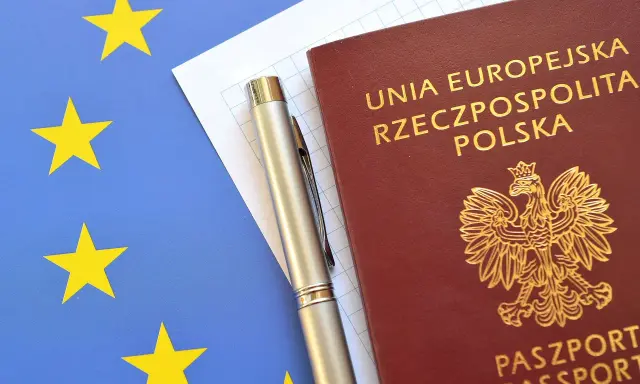 Polski paszport, długopis i flaga Unii Europejskiej.