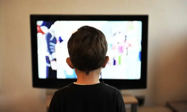 Un jeune enfant de 2 ans, absorbé par un dessin animé coloré sur le téléviseur.