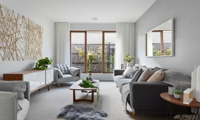 Elegante salón donde el gris y beige combinan a la perfección, con sofás cómodos, mesa de centro de madera y una original decoración de ramas en la pared.