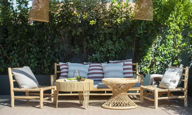 Un rincón acogedor para decorar terraza ático. Muebles de ratán, cojines y lámparas de mimbre crean un oasis natural.