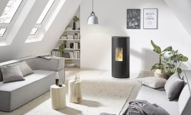 Poêle à granulés Rika en mode confort ou automatique, dans un salon moderne avec canapé gris, table basse en bois et lumière naturelle.