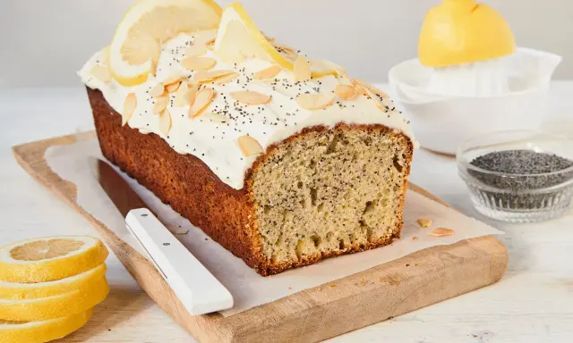 Saftiger zitronenkuchen mit mohn, garniert mit Mandelsplittern und Zitronenscheiben.