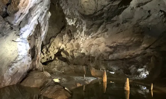Wnętrze jaskini Bielskiej z wodą i stalagmitami.