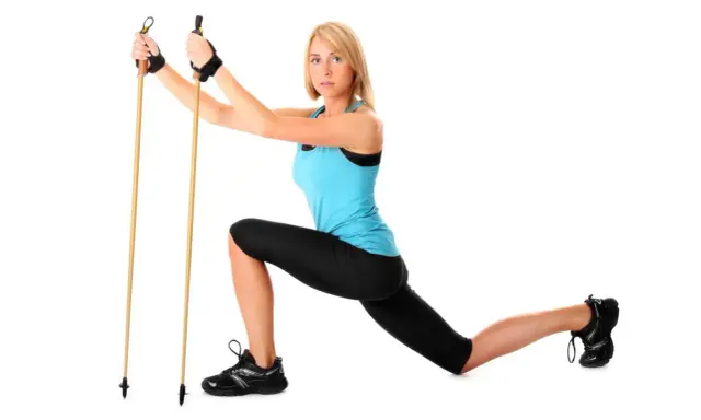 Kobieta w stroju sportowym demonstruje ćwiczenie z kijkami do nordic walking, pokazując, jak ustawić kijki do nordic walking.