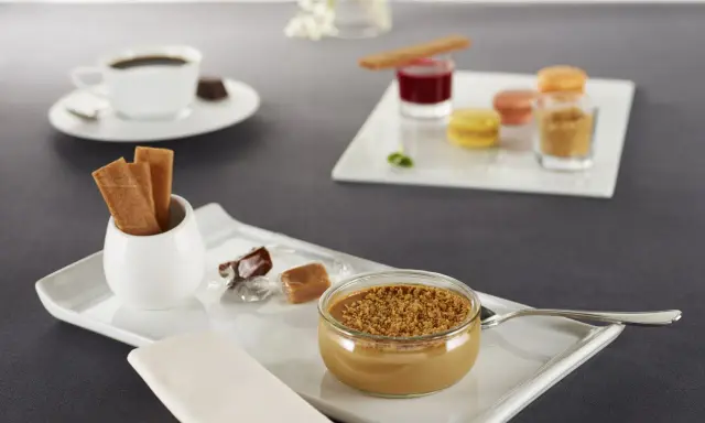 Un café gourmand avec diverses mignardises : verrine caramélisée, macarons, biscuits, chocolats. Idéal pour des recettes de mignardises pour café gourmand.