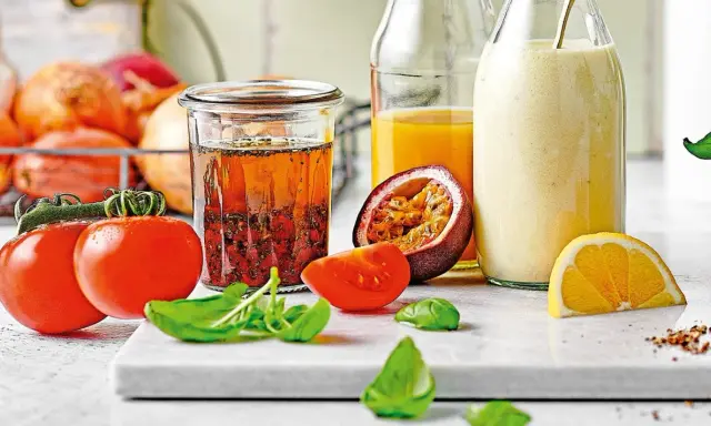 Ein Glas mit asiatischem Salatdressing, Tomaten, Passionsfrucht, Orange und Kräutern.