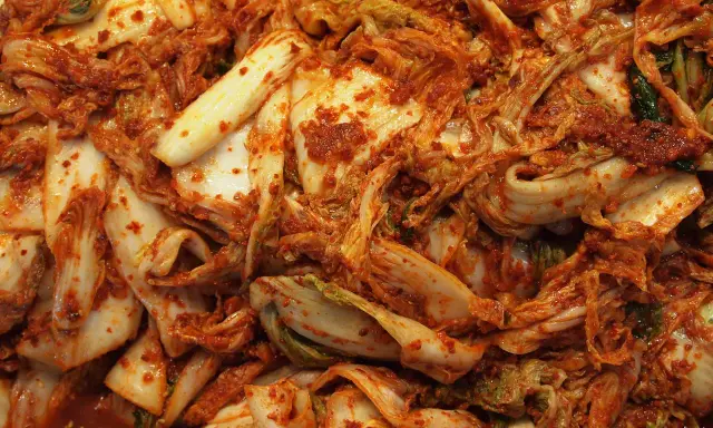Zbliżenie na świeże, pikantne kimchi z kapusty pekińskiej, pokryte czerwoną pastą chili.