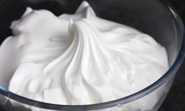 Merengue italiano esponjoso y brillante en un bol de cristal, listo para decorar postres.