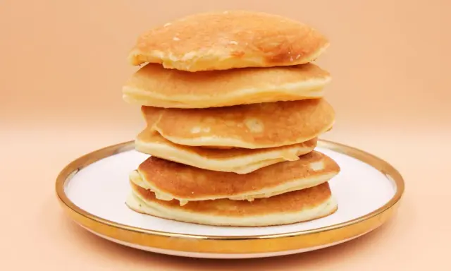 Stos puszystych, złotych pancake'ów na talerzu. Idealny przepis na śniadanie.