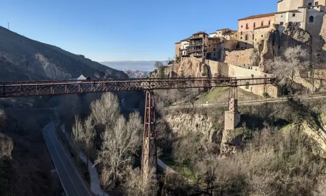 Puentes de Cuenca: una estructura de hierro cruza un barranco, con casas colgando de acantilados rocosos al fondo.