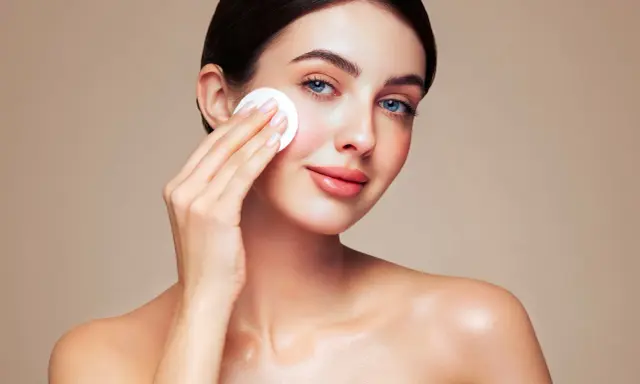 Une femme au maquillage impeccable utilise un coton pour se démaquiller, prouvant que le maquillage n'abîme pas la peau si on en prend soin.