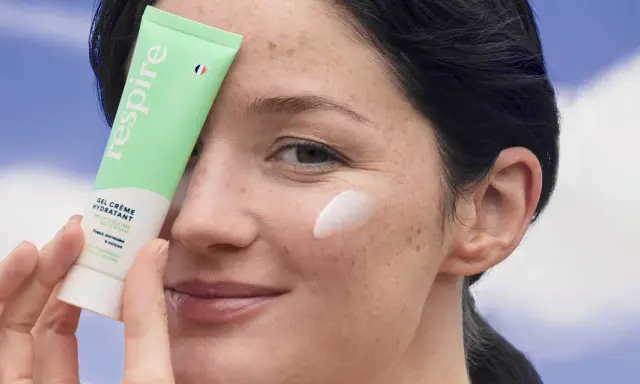 Une femme applique une crème hydratante sur sa joue. Une solution pour comment hydrater sa peau très sèche.