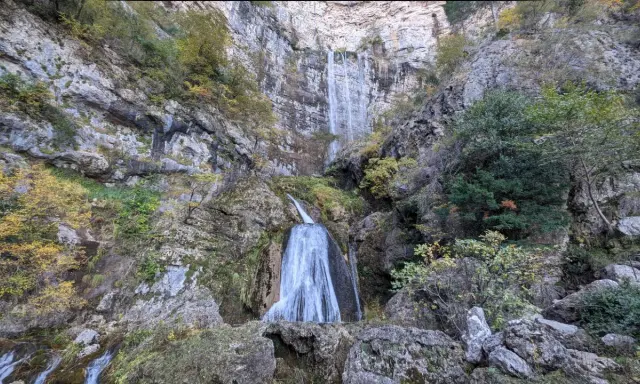Impresionante cascada en la ruta de las cascadas Bogarra, cayendo por una pared rocosa con vegetación otoñal.