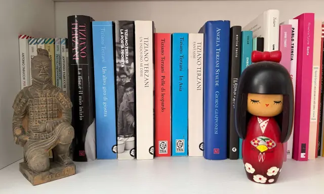 Statua guerriero terracotta e una collezione di libri di Tiziano Terzani, tra cui "La fine è il mio inizio" e "Un altro giro di giostra".