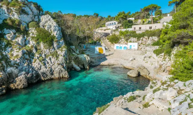 Baia incantevole con acque cristalline, perfetta per un itinerario Puglia 3 giorni. Case bianche e rocce a picco sul mare.
