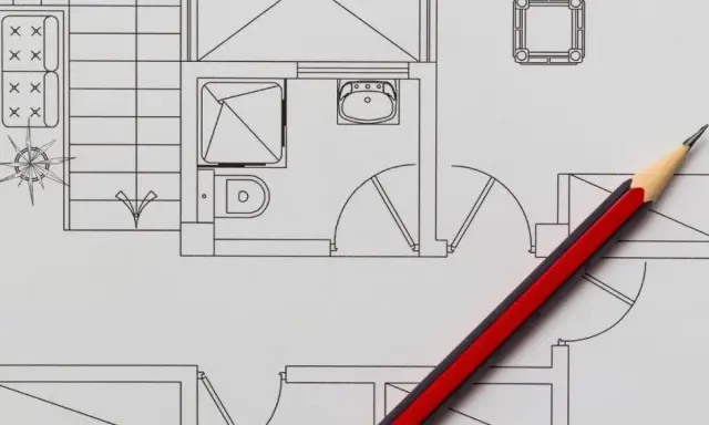 Un crayon rouge et noir sur un plan de maison, idéal pour faire un plan de maison gratuit et visualiser votre projet.