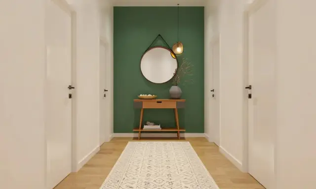Un couloir moderne avec un mur vert, un miroir rond, une console en bois et un tapis. Une belle idée déco couloir moderne.