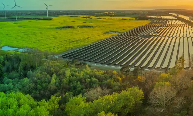 Weite Landschaft mit Windrädern, Solarpanels und grünen Feldern. Ein Zeichen für gesellschaftliche Akzeptanz erneuerbarer Energien.