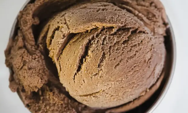 Une généreuse boule de glace au chocolat, crémeuse et givrée, dans un bol métallique.