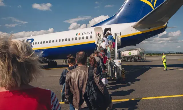 Pasażerowie wsiadają do samolotu Ryanair. Zastanawiasz się, ile kosztuje odprawa na lotnisku? Tutaj nie ma dodatkowych opłat.