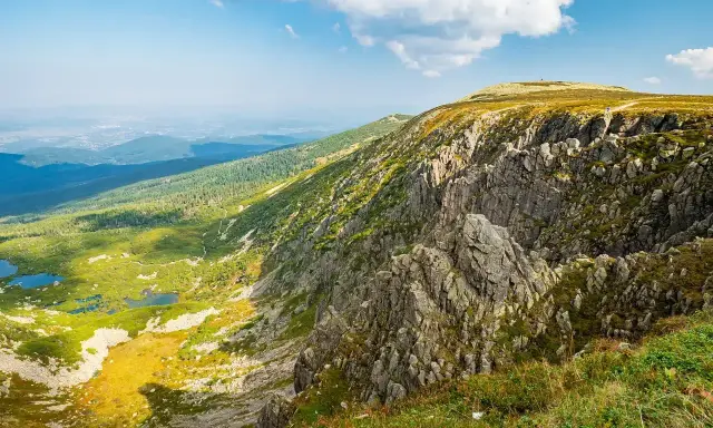 Widok na skaliste zbocze Szrenicy i malownicze Śnieżne Kotły z górskimi stawami w dole.