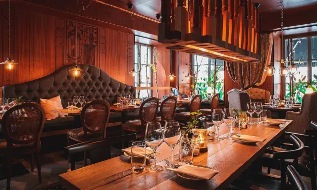 En klassisk restaurang i Gamla Stan med sammetsklädd soffa, rottingstolar och vackert dukade bord.