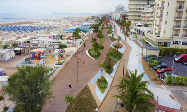 Passeggiata lungomare a Rimini Miramare con aree gioco, stabilimenti balneari e palazzi affacciati sul mare.